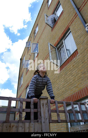 Un ebreo ortodosso boy arrampicata su una recinzione di fronte ad un blocco di appartamenti con le finestre aperte in Reizel chiudere un Agudas Israele Housing Association per lo sviluppo a basso reddito ebrea ortodossa le famiglie a Stamford Hill, Londra. Foto Stock