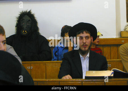 Un uomo vestito come un gorilla nella congregazione durante la lettura Megillah per la festa di Purim in strada Walford sinagoga. Purim è uno dei più divertenti vacanze ebraiche. Essa commemora il tempo quando il popolo ebraico vive in Persia furono salvati dallo sterminio da un massacro da Haman. Grazie al coraggio di una giovane donna ebrea chiamato Esther, è consuetudine per gli uomini vestito u e a tenere il carnevale-come celebrazioni. Foto Stock