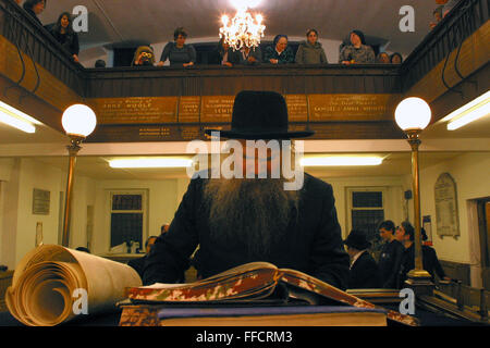 Rabbi Herschel Gluck di strada Walford Sinagoga legge la Megillah 'La chiocciola di Esther' durante la festa ebraica di Purim. Le donne e i bambini ascoltare il Rabbino da un balcone al primo piano. Foto Stock