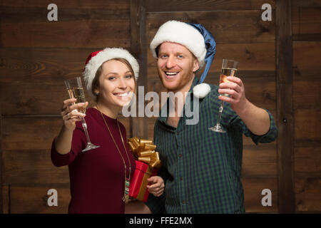 Coppia felice in cappelli di Babbo Natale con bicchieri di shampagne Foto Stock