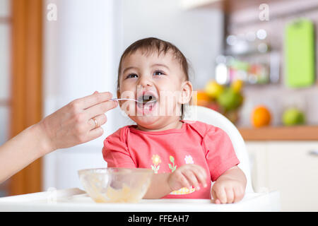 Madre alimenta funny baby da un cucchiaio Foto Stock