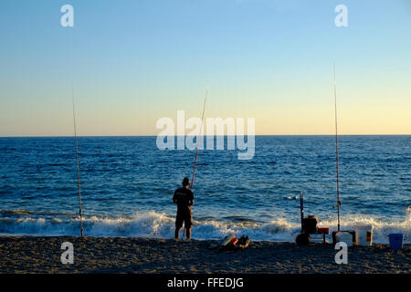 Lone pescatore dalla spiaggia come il sole scende. Almuñécar, Granada, Andalusia. Spagna Foto Stock