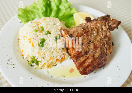 Bistecca di pollo con riso e lattuga su piastra bianca Foto Stock