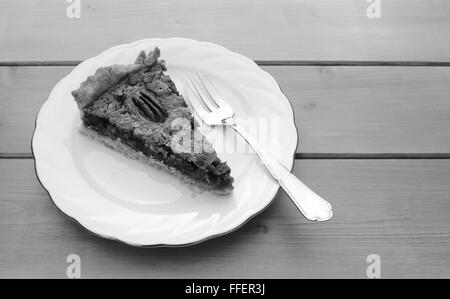 Fetta di appena sfornato torta alle noci pecan su una piastra in Cina con un dessert fork - elaborazione monocromatica Foto Stock