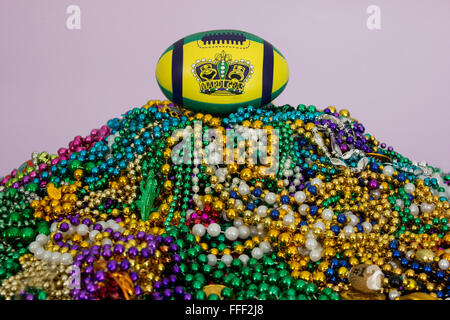 Mardi Gras maschere e re la corona stampato su un football americano, arroccato sulla cima di un enorme pila di Mardi Gras perline. Foto Stock