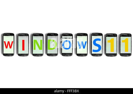 Windows 11 scritto sugli schermi di smartphone fotografati contro uno sfondo bianco. Foto Stock