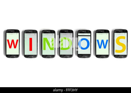 Windows scritto su schermi di smartphone fotografati contro uno sfondo bianco. Foto Stock