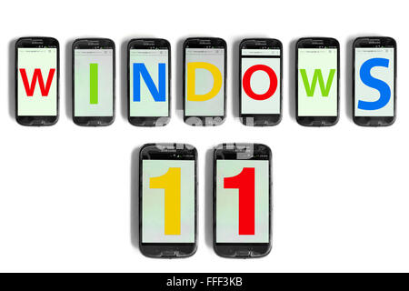 Windows 11 scritto sugli schermi di smartphone fotografati contro uno sfondo bianco. Foto Stock