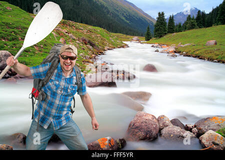 Uomo turistica con uno zaino e della pala sul fiume di montagna sullo sfondo Foto Stock