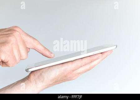 Maschio di mano azienda moderna compressa o grandi smart phone. Altro lato rivolto verso lo schermo del dispositivo mobile con un dito di una mano. Concetto di Foto Stock