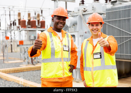 I tecnici di allegro dando pollice in alto nella sottostazione Foto Stock
