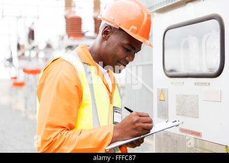 Bello africano tecnico industriale prendendo letture macchina Foto Stock