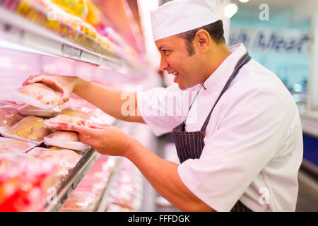 Felice di media età del macellaio il lavoro in macelleria Foto Stock