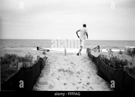 Jan 4, 2016 - South Beach, KwaZulu-Natal, Sud Africa - un uomo a piedi attraverso le dune su South Beach. South Beach è una parte della città di Durban è ininterrotta più lunga striscia di spiaggia di sabbia. La città di Durban si trova sulla costa orientale del Sud Africa e la gente di qui vengono lavati con le calde acque dell'Oceano Indiano. A nord di questo tratto di sabbia sono spiagge con cafe society hang outs. A sud si trova un molo con la sistemazione di Moyo del ristorante al suo fine e l'Ushaka Marine World complesso e il privato e surf club del mare delle vecce area di spiaggia. Tra questi n Foto Stock