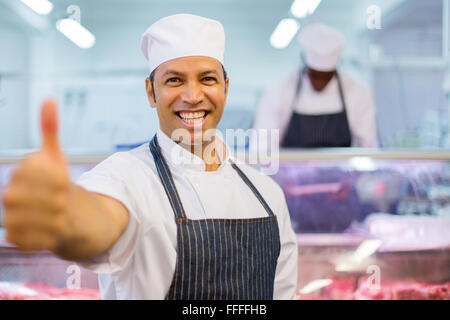 Allegro macellaio maschio pollice in alto nella macelleria Foto Stock