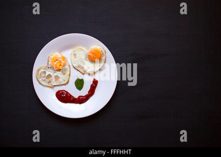 La prima colazione, uova fritte in forma di cuori, Smile, buon umore, mattino luminoso, sfondo Foto Stock