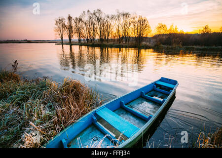 Lago, Fiume e vecchio blu in legno a remi in barca da pesca alla bellissima alba in autunno la mattina. Foto Stock