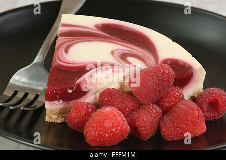 Porzione di lampone ripple cheesecake con lamponi freschi Foto Stock