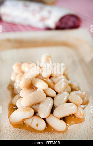 Servire di fagioli cannellini con salame su di un piatto di legno Foto Stock