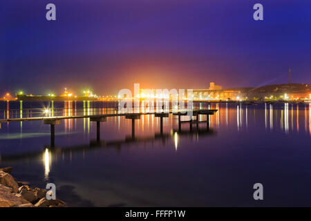 Luci del molo e distante carico porto pontili di Esperance in Western Australia. Sunrise oltre ancora le acque della baia in locali di piccole dimensioni Foto Stock