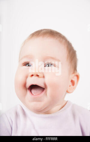Ritratto di otto mesi di età adorabile bionda simpatico baby in velluto rosa sorridente onesie faccia felice isolato su bianco Foto Stock