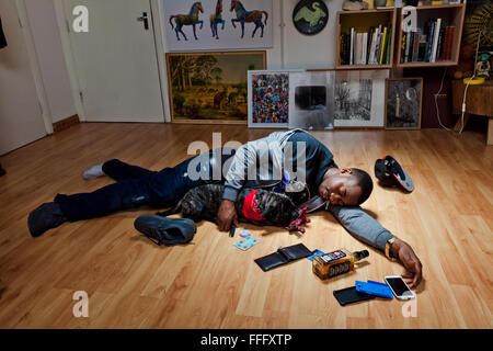 Giovane uomo dorme sul pavimento con un cane lasciando un mass. Foto Stock