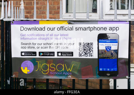 Un banner al di fuori di una scuola primaria incoraggia i genitori a scaricare un'app smartphone per ricevere notizie e informazioni. Foto Stock