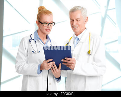 Immagine del team medico consulting. Ritratto di medico donna azienda appunti e la consultazione con i senior medico mentre un permanente Foto Stock