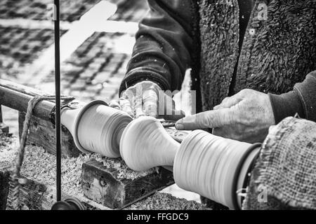 Un artigiano si ritaglia un pezzo di legno utilizzando un vecchio manuale tornio. Foto Stock