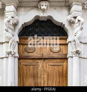 Vecchia pietra bianca ingresso e portale in legno con le statue che supportano le colonne laterali. Foto Stock