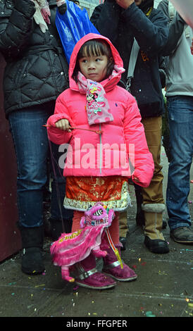 Un bel 5 anni cinese ragazza in un abito di fantasia e di un piccolo drago al nuovo anno lunare parade. Mott St in Chinatown, NYC Foto Stock