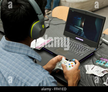 L'uomo la riproduzione video Xbox gioco sul computer portatile e cuffie - USA Foto Stock