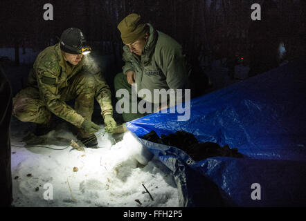 Il personale Sgt. Seth Reab, det. 1, 66Training Squadron, Arctic sopravvivenza istruttore della Scuola, legami verso il basso un termalizzati telaio a riparo durante la sopravvivenza artica a fianco di formazione Capt. Bart Spendley, 274th aria funzionamento supporto Squadron, aria liaison officer. Il telaio a ricovero è progettata per tenere il sopravvissuto caldo e asciutto a sopportare dure la notte artica. Il corso è di cinque giorni di durata con le istruzioni nella familiarizzazione con l'ambiente artico, medico, protezione personale, il sostentamento e la segnalazione. Foto Stock