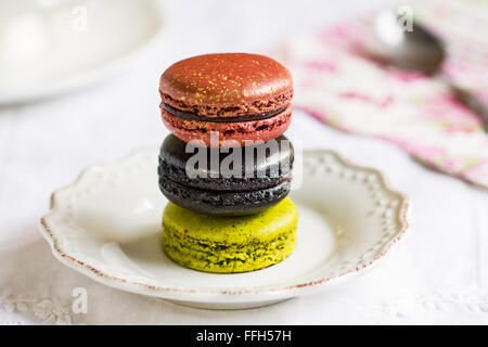 Matcha,tartufo nero e rosa Macaron con la formazione di polvere di oro su un piatto da caffè Foto Stock