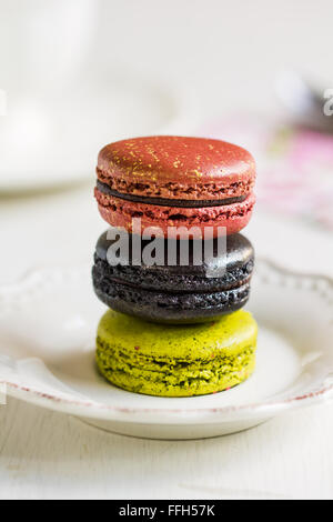 Matcha,tartufo nero e rosa Macaron con la formazione di polvere di oro su un piatto da caffè Foto Stock