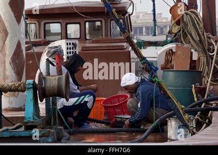 I pescatori gut e pulire i gamberi in una barca Foto Stock