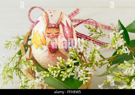 Dipinto a mano e decoupage decorato uovo di pasqua tra fiori di sambuco Foto Stock