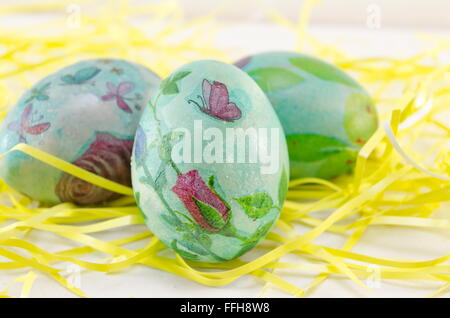 Dipinto a mano decoupage uova di Pasqua nel fieno come cannucce Foto Stock