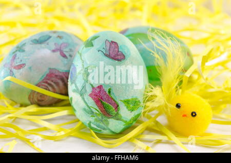 Dipinto a mano decoupage uova di Pasqua nel fieno come cannucce Foto Stock