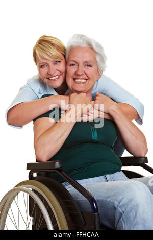 Donna felice abbracciando disabili donna senior in carrozzella Foto Stock