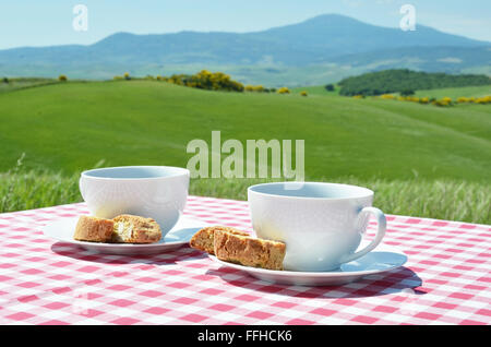 Due tazze di caffè sul tavolo di legno contro il paesaggio toscano, Italia Foto Stock