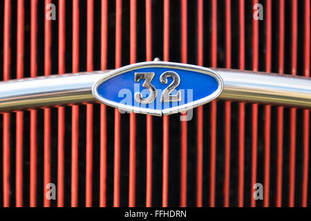 Il numero 32 entro una targa blu, parte di chrome bar nella parte anteriore di un colore rosso brillante auto grill Foto Stock