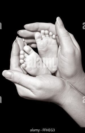 Un'immagine dell'attraversato i piedi di un neonato con gli anelli di nozze su le sue dita, tazza nelle sue mani le madri Foto Stock