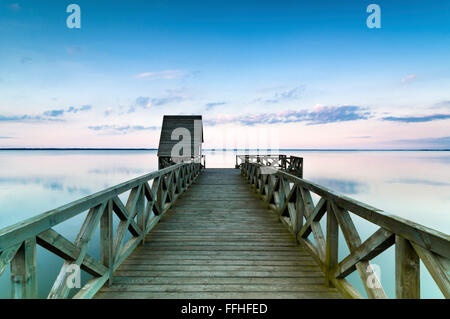 Colorato tramonto sul lago calmo visto da un ponte di legno Foto Stock