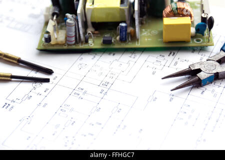 Scheda a circuito stampato con un componente elettrico e strumenti di precisione giacente sul disegno di costruzione di elettronica. Foto Stock