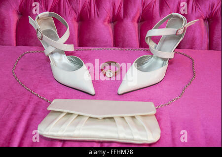 Primo piano dettaglio delle spose alta sandalo con tacco Scarpe su un divano rosa con orologio d'oro e borsetta Foto Stock