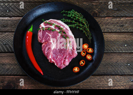 La cottura di una bistecca in padella con il timo e il peperoncino. Immagine di stock. Foto Stock