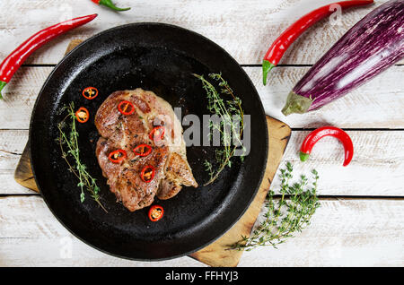 La cottura di una bistecca in padella con il timo e il peperoncino. Immagine di stock. Foto Stock