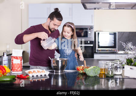 Padre insegna la figlia di cucinare a casa in cucina. Immagine di stock. Foto Stock