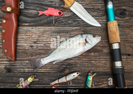 Asta di filatura, aspo e di esche da pesca isolato su sfondo di legno, vista dall'alto Foto Stock